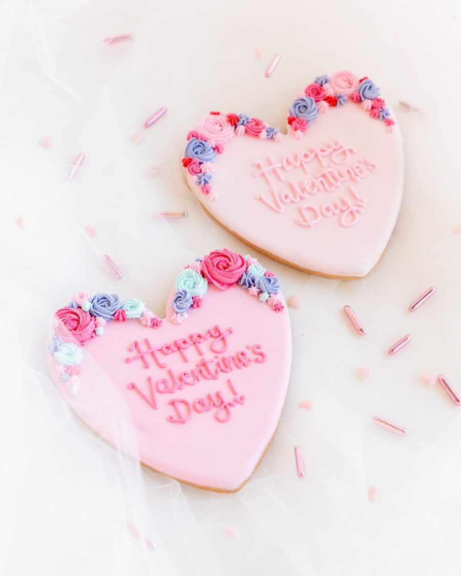 Extra Large Valentine’s Cookie Royal Icing Floral Design Two heart-shaped Valentine’s cookies with piped royal icing flowers and embossed messages.