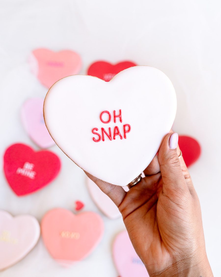 Detailed close-up of fondant heart cookies with Valentine’s sayings in pink and red.